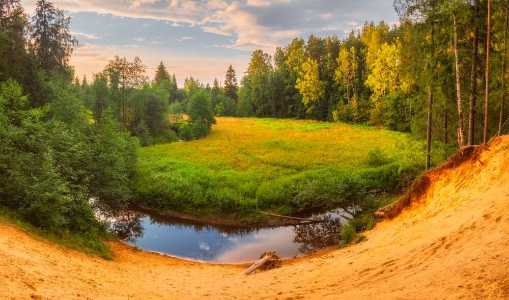 Песчаный утес на извилистой реке Охте в осеннем лесу 