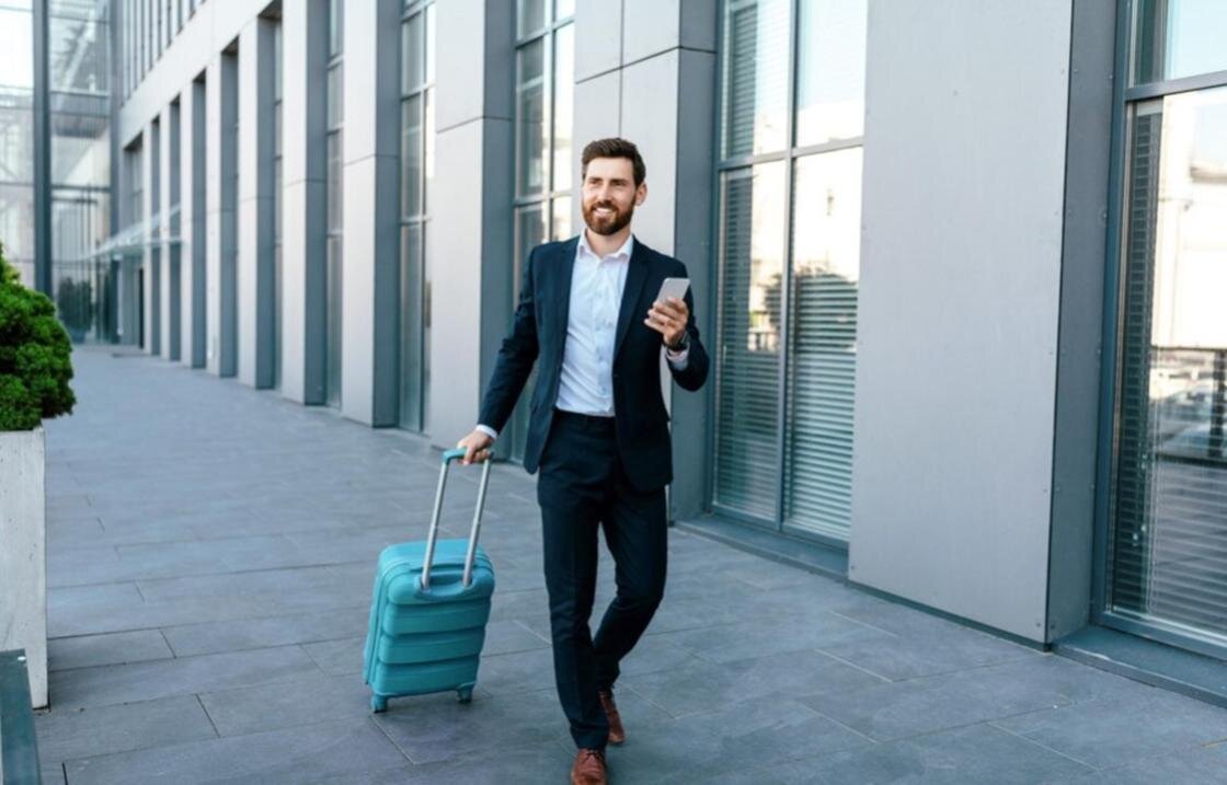    Мужчина с чемоданом и смартфоном в руках:Freepik