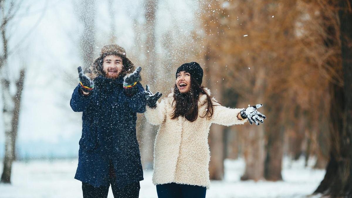    Парень и девушка бросают снег и смеются:Freepik