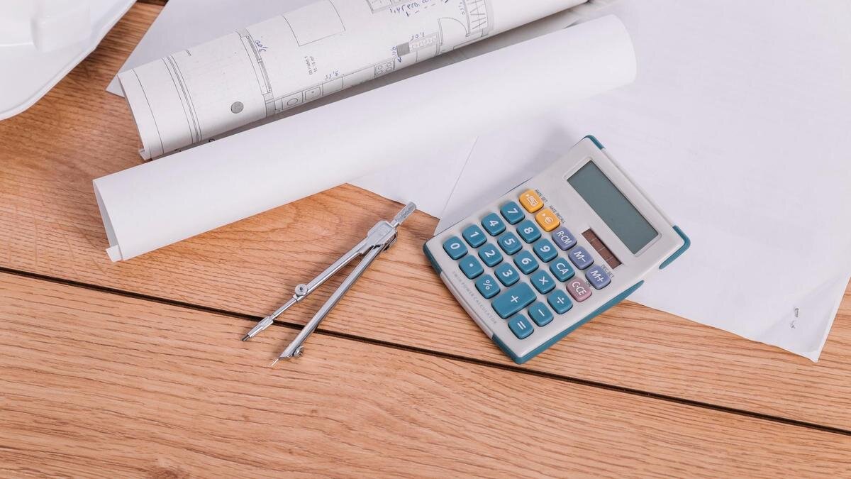    На столе на чертежах лежит калькулятор и циркуль:Freepik/Freepik