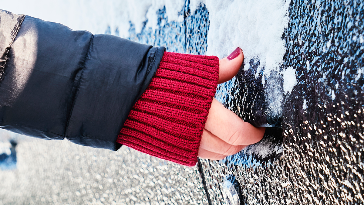 Попытка открыть замерзшую дверь автомобиля. Источник изображения: Maryshot / Shutterstock.com