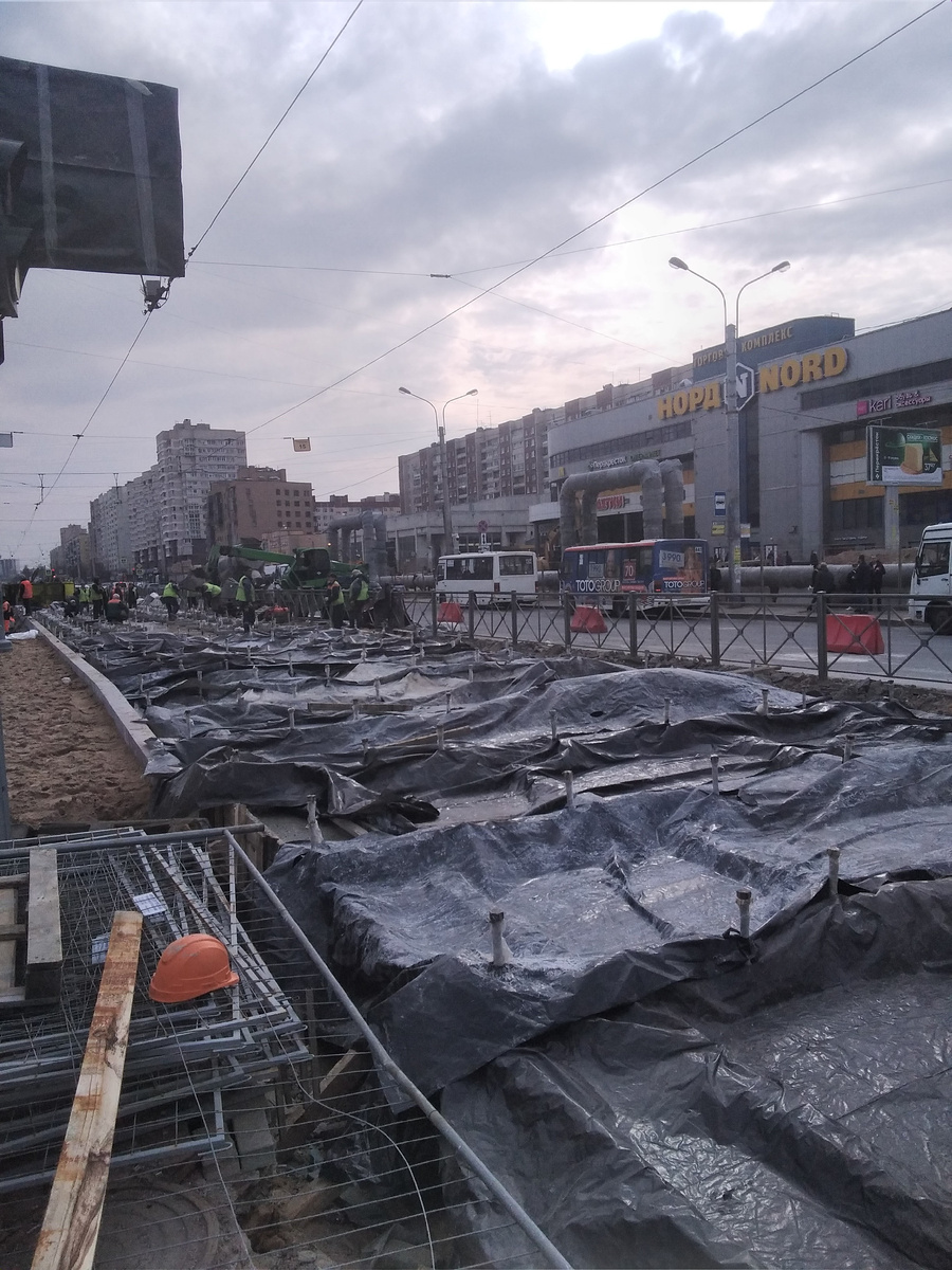 Там, где повилась новая посадочная платформа, там рельсы лежат на бетонной подушке. Пока бетон застывает, его накрыли брезентом от осадков  
