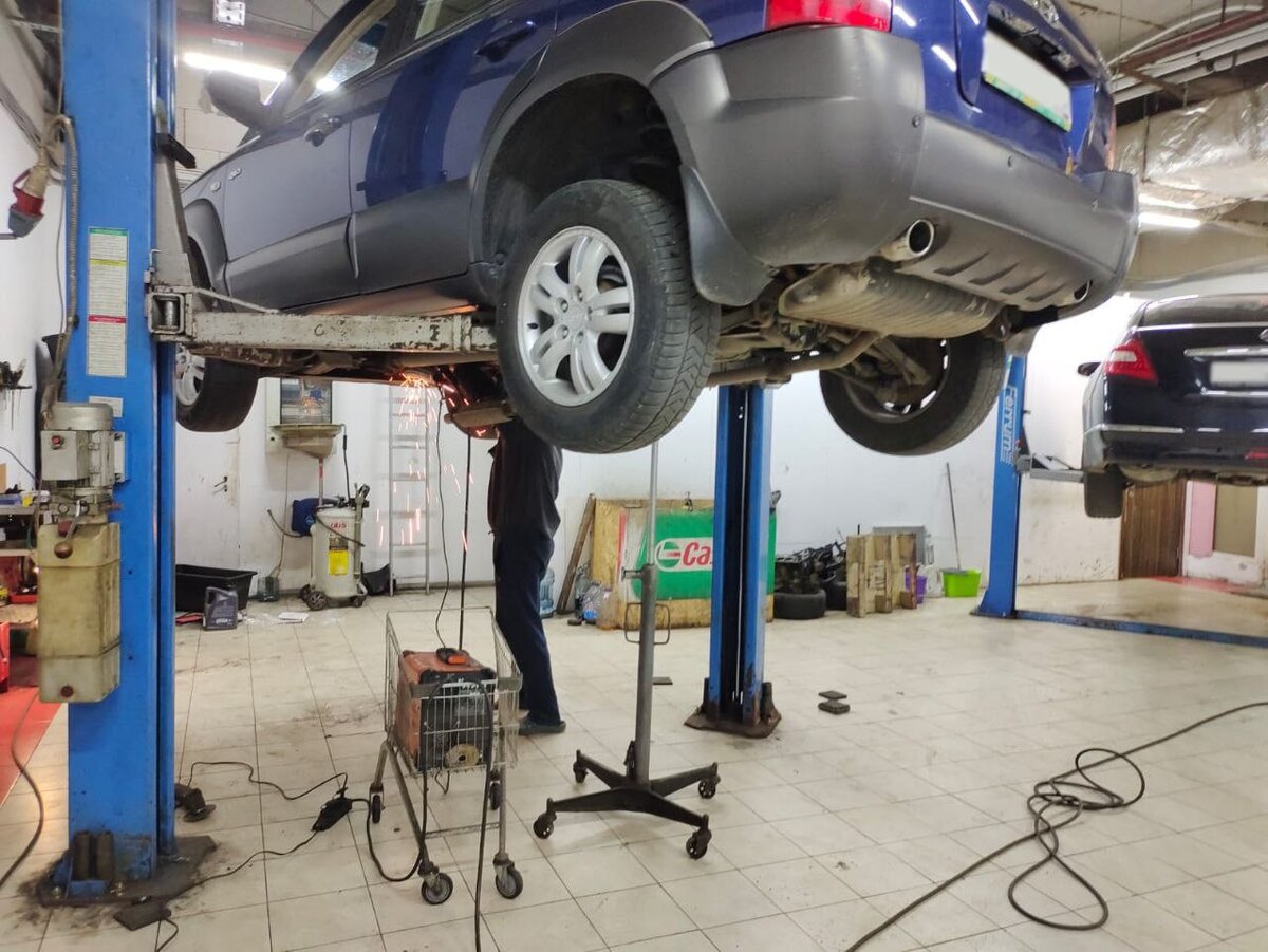 автослесарь Николай меняет гофру на глушителе 