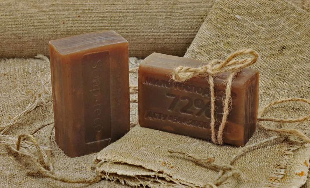 кусок хозяйственного мыла в руке. почему хозяйственное мыло. мыло. хозяйственное мыло коричневое. брусок хозяйственного мыла.