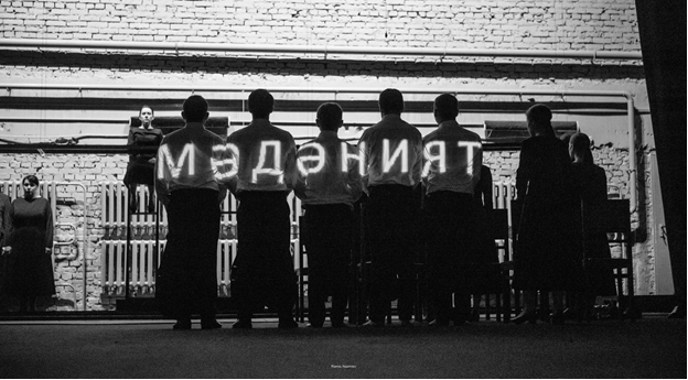 Сцена из спектакля «Место есть лишь в тишине». Глава Х «Культура» - название главы высвечивается на спинах людей. Фото с официального сайта Альметьевского драматического театра