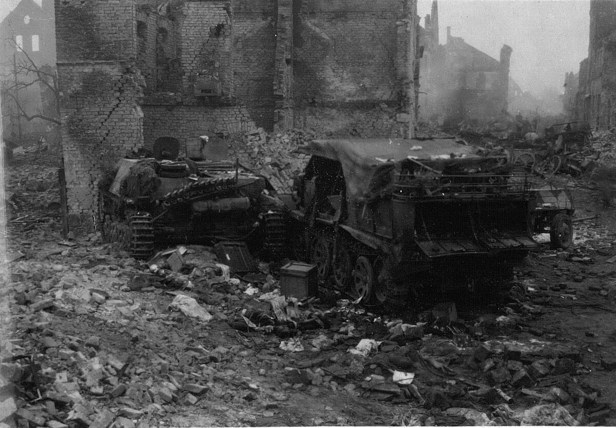 Подбитые советскими войсками немецкий истребитель танков Jagdpanzer IV/70 (слева) и полугусеничный тягач Sd.Kfz.7 на улице города Фишхаузен (ныне город Приморск в Балтийском муниципальном районе Калининградской области). Фото из журнала боевых действий 1-й гвардейской штурмовой авиадивизии за апрель 1945 года. Источник фото: https://waralbum.ru/184217/