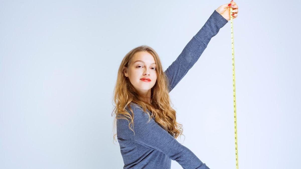    Девушка держит в руке сантиметр:Freepik