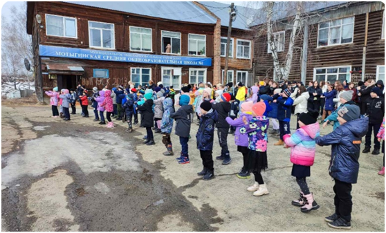 Фотография № 2. Учащиеся 1-11 классов МСШ № 1 на общешкольной музыкальной разминке, посвященной Дню Здоровья. Дата съёмки: 06.04.2023. Координаты фотографа: 58,1844 гр с.ш., 94,6664 гр в.д.  В центре кадра есть береза. Справа от неё на втором этаже видно большое окно. Это и есть окно класса русского языка и литературы, закреплённого за Ершенко А.И. в 1982-1984 годах.
Фотография взята с сайта МСШ № 1: https://sh1-motygino-r04.gosweb.gosuslugi.ru/roditelyam-i-uchenikam/novosti/novosti_6.html.