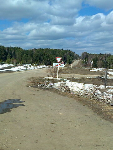 Фотография № 2. Весна 2014 года. Вид на дорогу Рыбное-Бельск от поворота этой дороги у села Рыбного на паромную или ледовую переправу. На уровне дорожного знака «Уступи дорогу» видна первая горка от Рыбного. Сразу на этой горке налево уходила дорога на нижний склад Мотыгинского ЛПХ, расположенного на Чёрной речке. Это и была чернореченская дорога на пасеку.