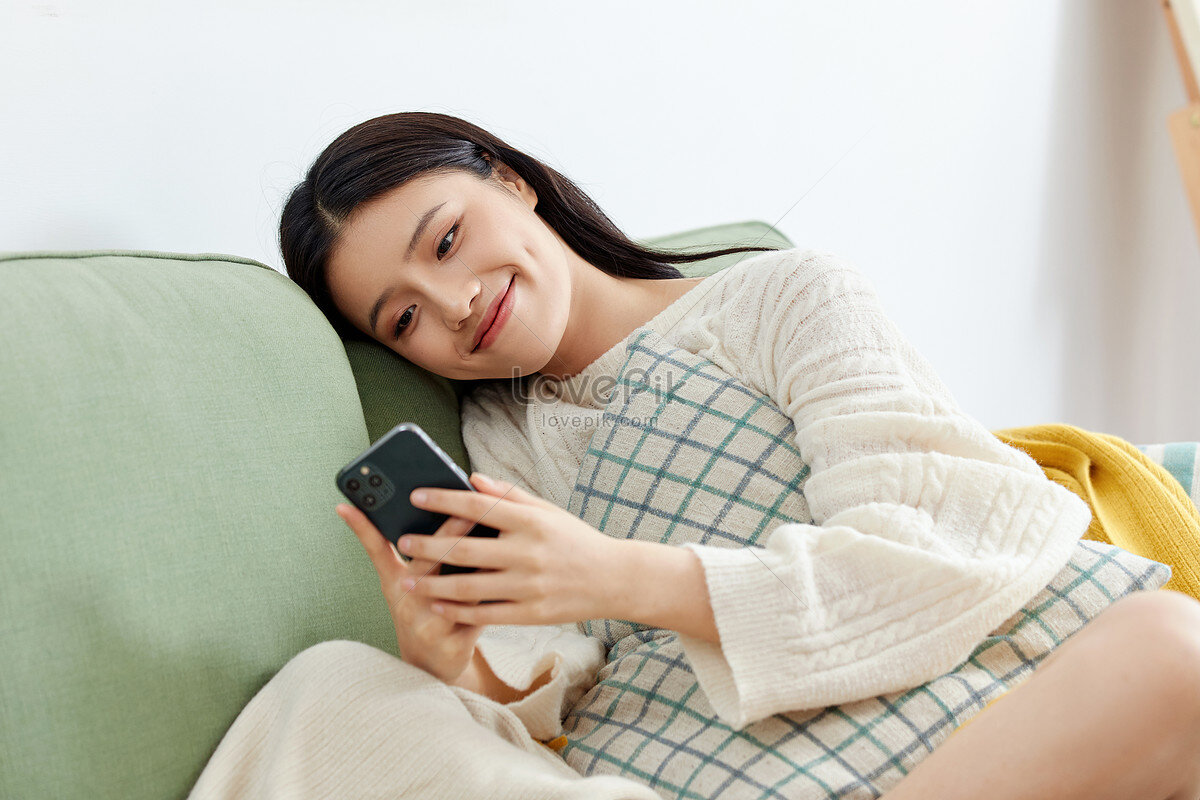 https://ru.lovepik.com/image-501433712/beautiful-home-girl-sitting-on-the-sofa-playing-with-mobile.html