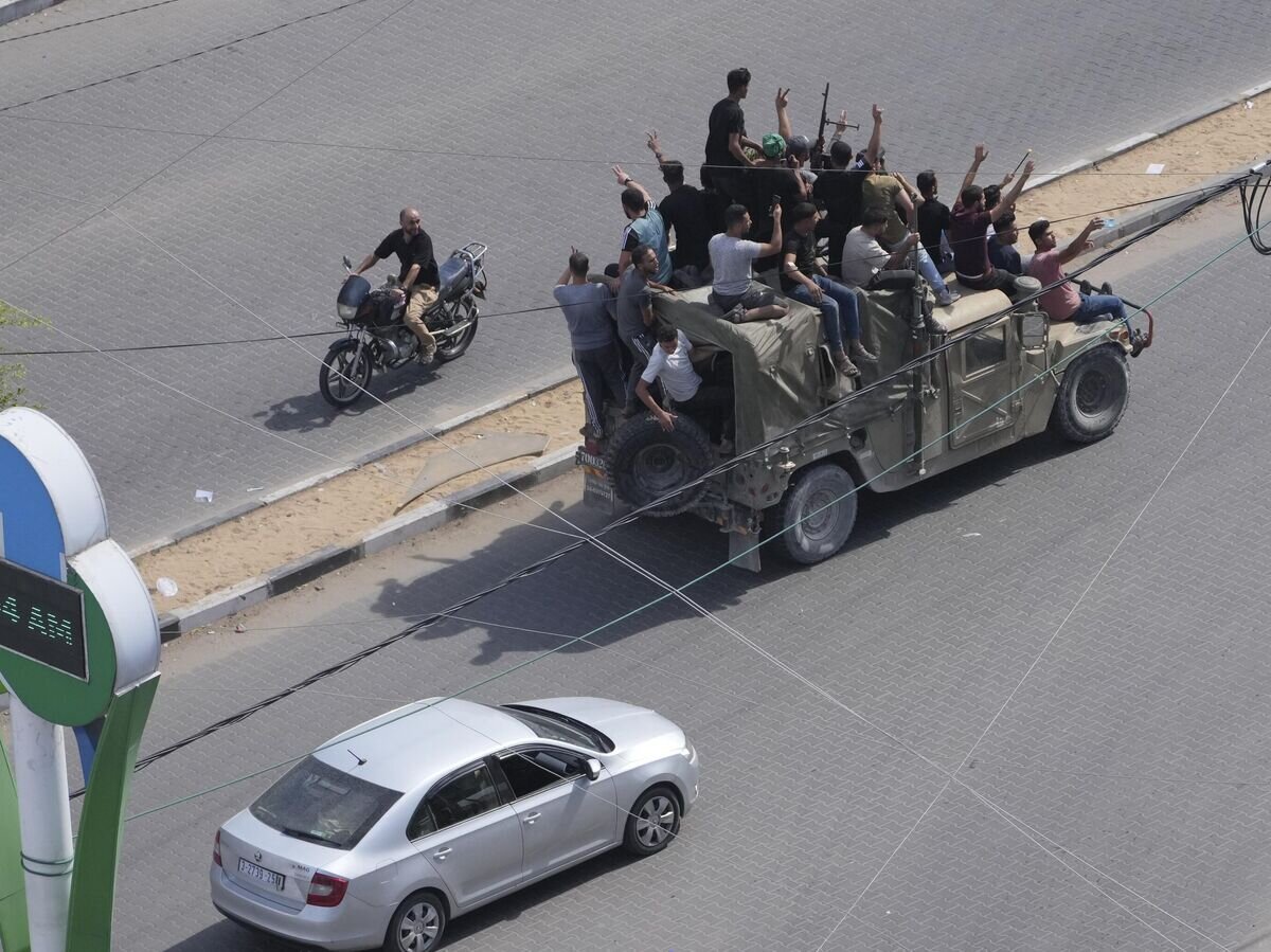    Палестинские бойцы едут на захваченной израильской военной машиной в секторе Газа© AP Photo / Hatem Moussa