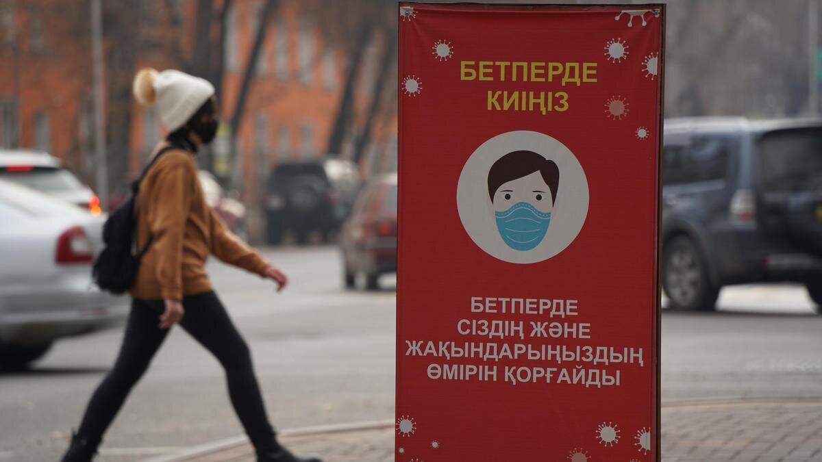    Девушка в белой шапке идет позади баннера:NUR.KZ / Владимир Третьяков