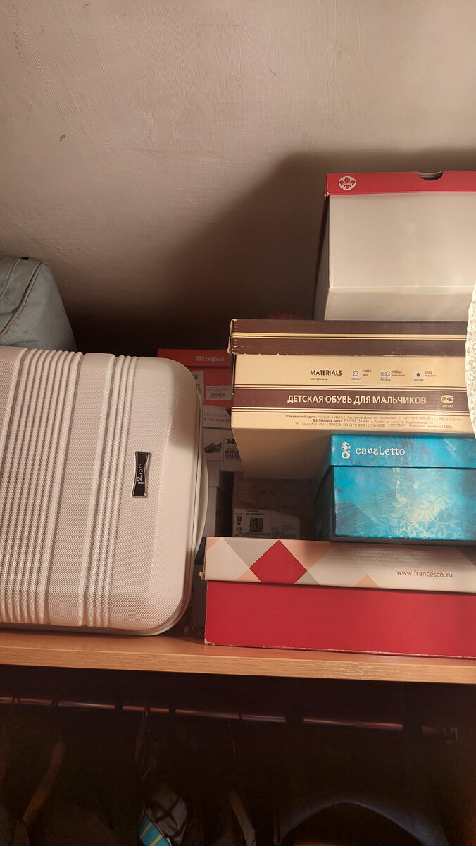 Неподписанные коробки с обувью ещё и прячутся за чемоданом.