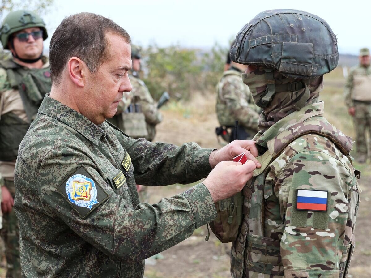    Заместитель председателя Совета безопасности РФ Дмитрий Медведев награждает бойца ВС РФ во время посещения полигона подготовки военнослужащих, набранных по контракту© РИА Новости