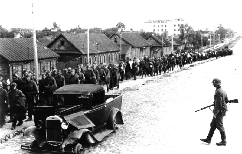 Первые недели Великой Отечественной войны. Колонна советских военнопленных и конвоирующие их немцы на улицах Минска. (2 июля 1941 года). Атрибуция фото: Bundesarchiv, Bild 146-1982-077-11 / CC-BY-SA 3.0.
