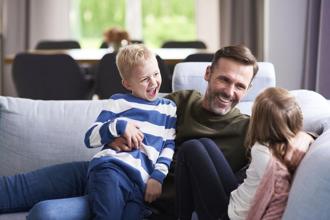    Мужчина сидит на диване с детьми:Freepik