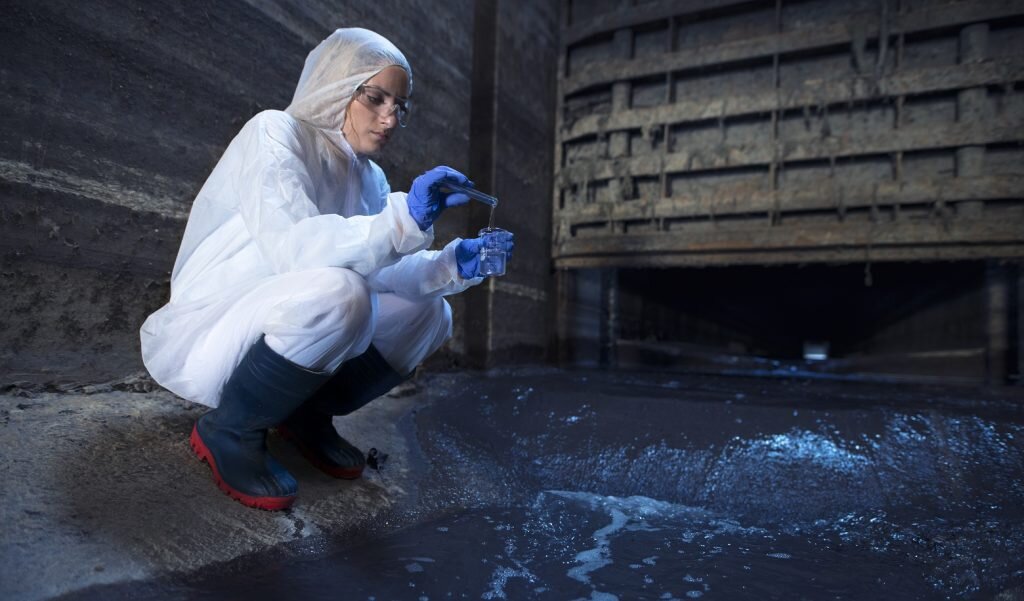    Ecologist expert taking water samples to examine pollution and contamination of waste water coming out of city sewage to the river. Андрей Елагин