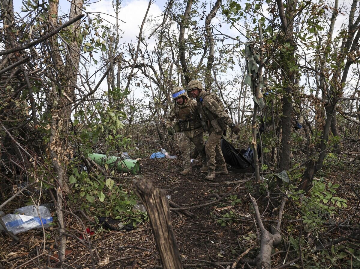    Украинские военнослужащие несут мешок с трупом убитого украинского солдата в Донецкой области© AP Photo / Alex Babenko