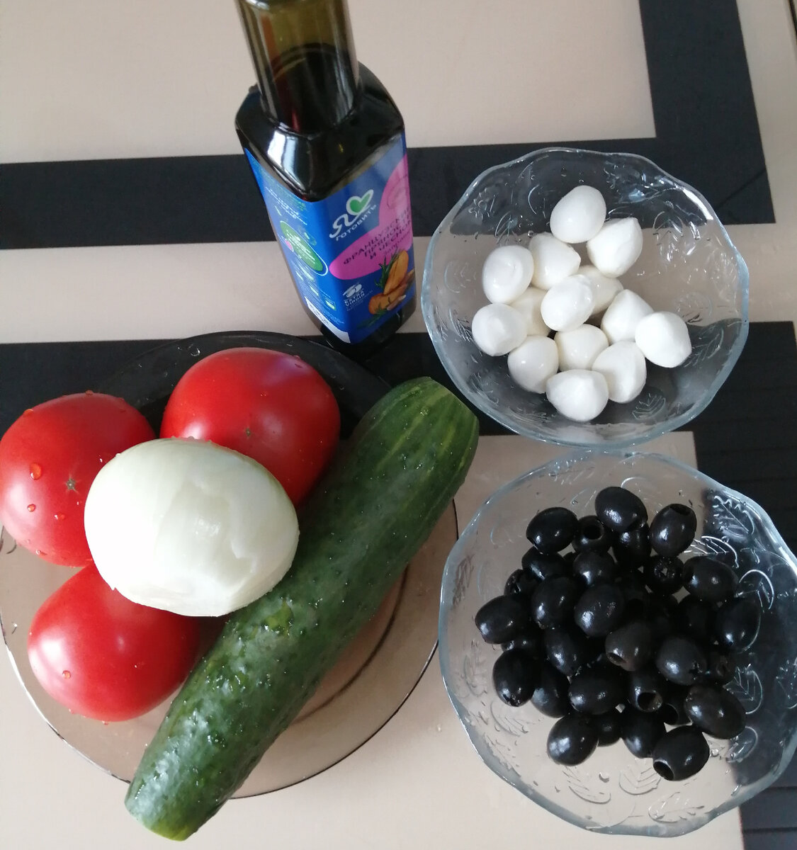 Огурец, помидоры, лук, баночка маслин без косточки, сыр моцарелла в шариках, зелень по желанию и масло для заправки салата.