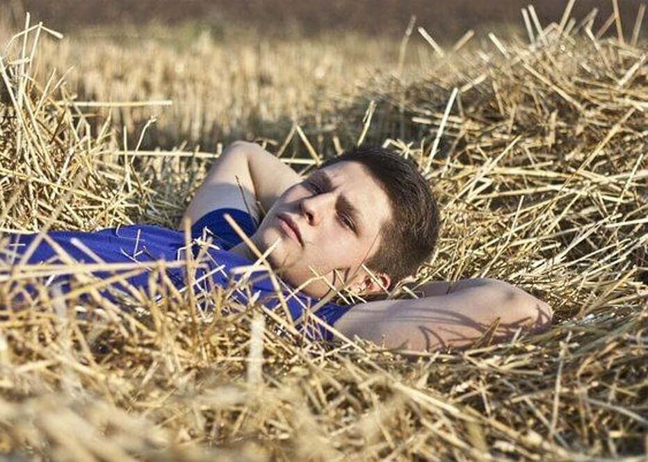 Номер лежит на поле. Парень лежит в поле. Парень на сене. Мужская фотосессия в поле. Человек лежит на сене.