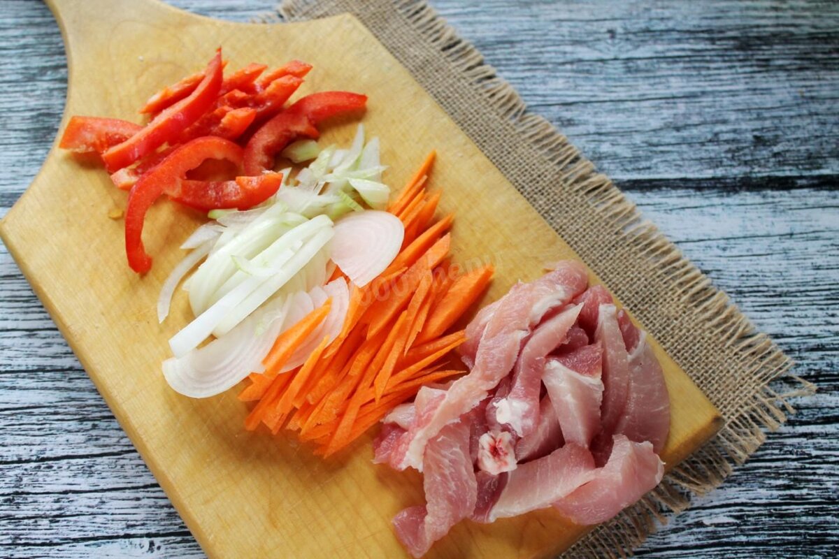 Морковь нарежьте тонкой соломкой, немного более крупной соломкой нарежьте болгарский перец. Мясо нарежьте тонкими ленточками, а лук - полукольцами. Так как китайская кухня отличается быстрой обжаркой и последовательной закладкой продуктов, т.е. времени на нарезку в процессе приготовления может просто не хватить, то нарежьте все ингредиенты до начала готовки.