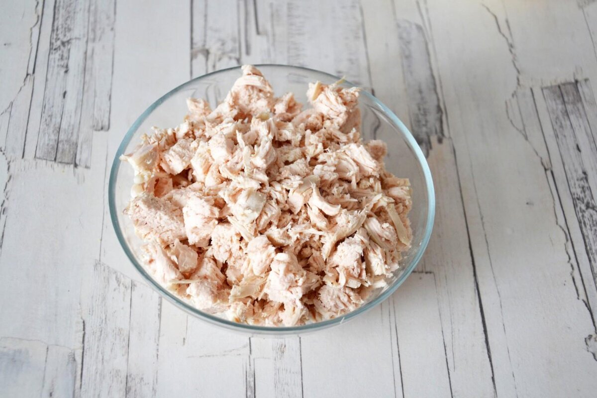 Налейте в кастрюльку примерно 1,5 литра воды. Когда закипит, подсолите (около 0,5 ст. л.соли) и отправьте туда курицу. Для вкуса можно добавить черный перец горошком (3-4 шт) и лавровый лист. Варите на небольшом огне под крышкой до готовности (приблизительно 20 минут после закипания). Если филе легко протыкается ножом, значит готово. Охладите, не вынимая из бульона, чтобы мясо не пересохло. Нарежьте маленькими кусочками.