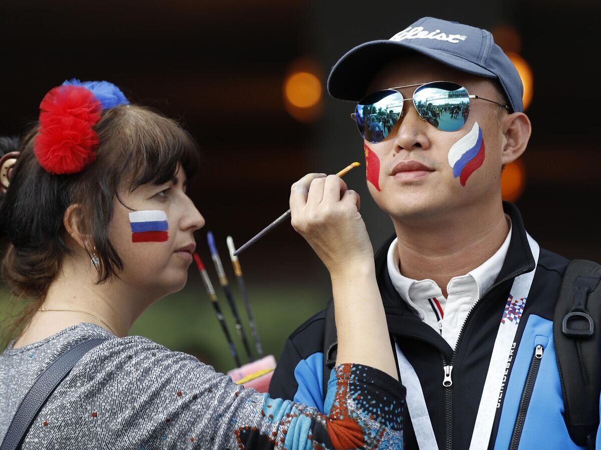    Девушка рисует флаг Китая на щеке молодого человека © AP Photo / Rebecca Blackwell