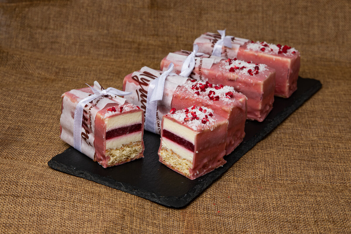 Кокосовый дакуаз с хрустящим слоем, начинка из пюре малины с добавлением цедры лайма, кокосовый мусс с ликером Малибу, а сверху рубиновый шоколад.