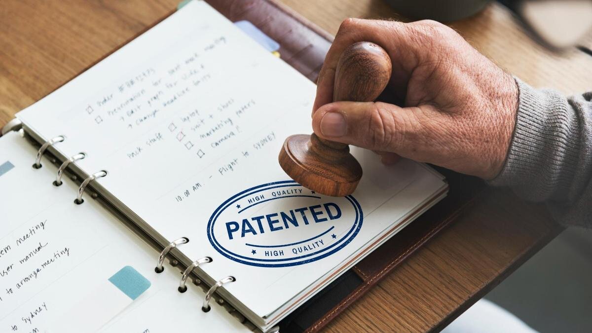    Рука пожилого мужчины ставит печать на документе PATENTED:Freepik/rawpixel.com