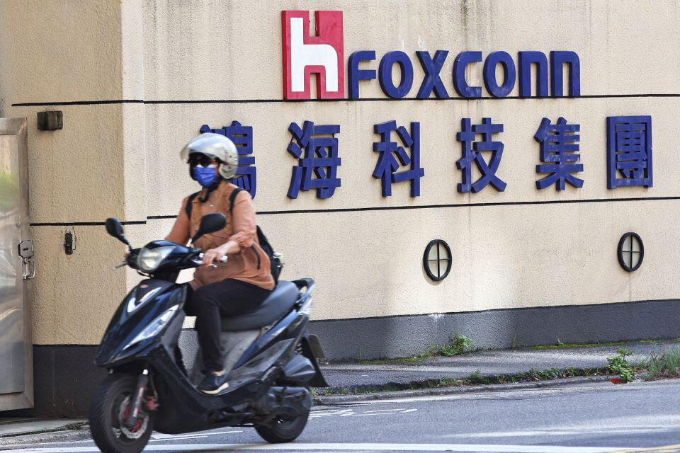 Женщина проезжает мимо логотипа Foxconn у здания компании в Тайбэе, Тайвань.