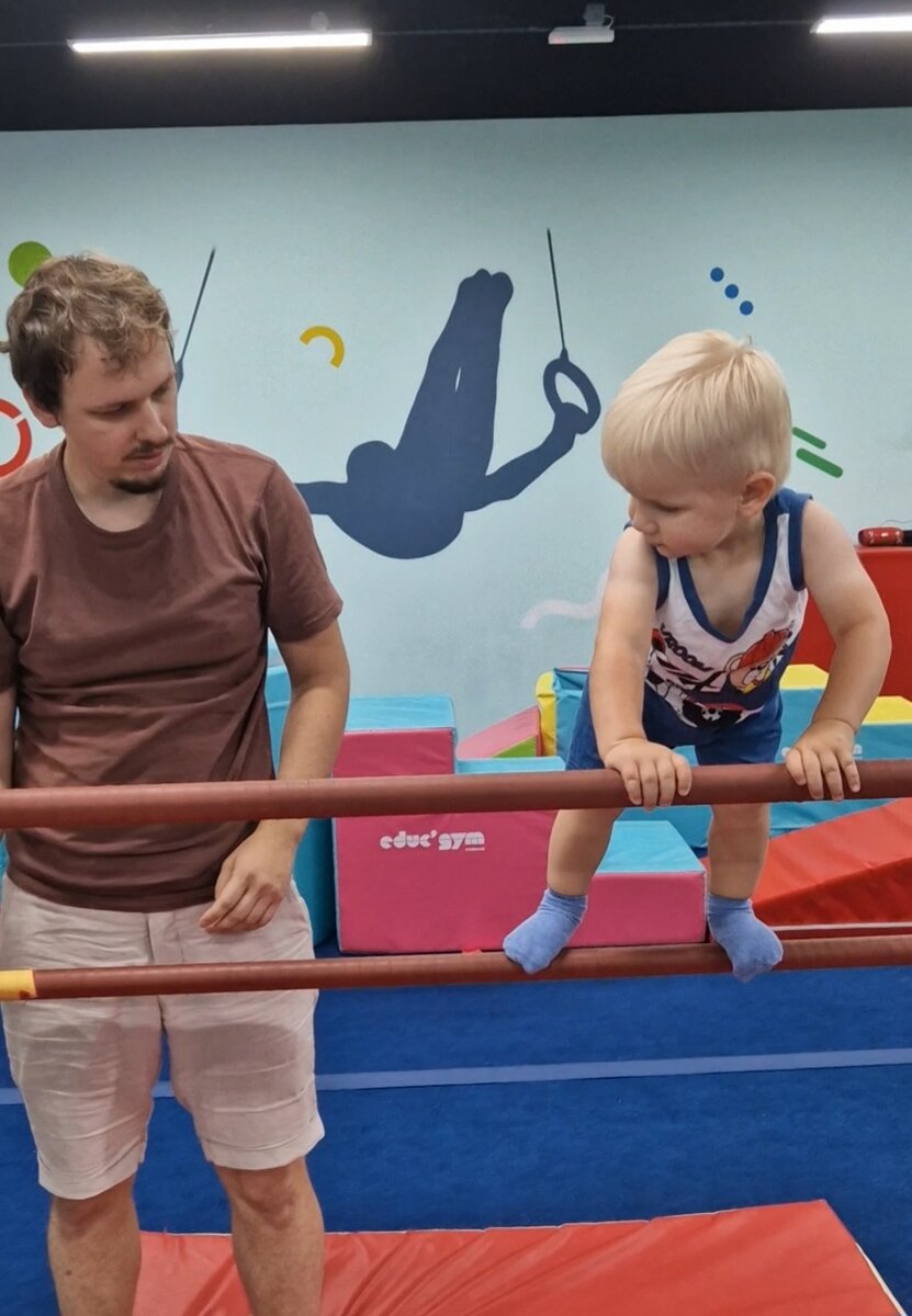 Ходит по брусьям в гимнастическом зале