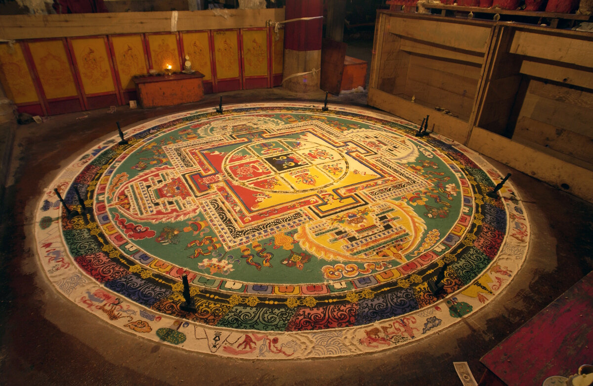 Изображение мандалы Калачакра достаточно регламентировано, монахи не фантазируют. Для оценки масштабов работы: диаметр круга около 5-6 метров. А в работе участвовало 8 монахов. 
