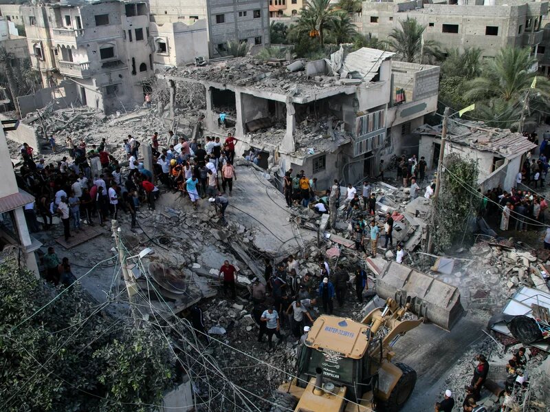 Палестинские службы экстренной помощи и местные жители ищут жертв в зданиях, разрушенных во время налетов израильской авиации на юге сектора Газа 18 октября 2023 года в Хан-Юнисе, Сектор Газа