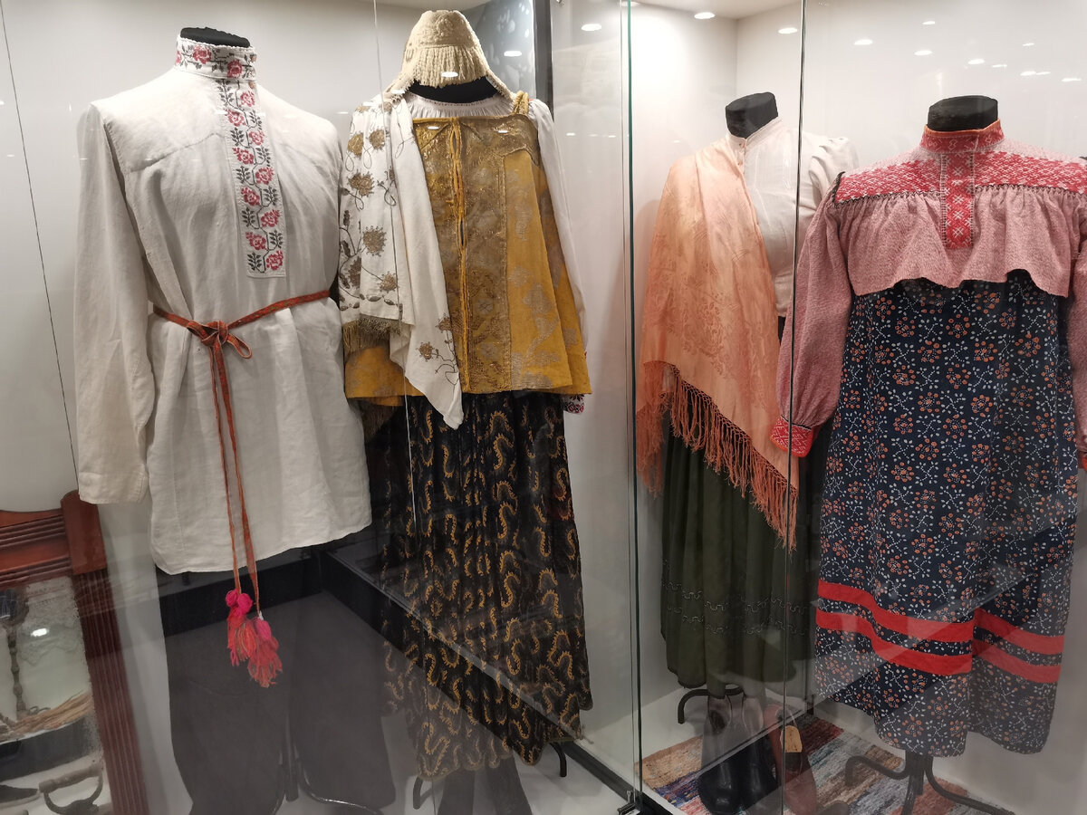 Свадебный наряд. Головной убор невесты полностью расшит речным жемчугом. Мелкий жемчуг размером с бисер. Десятки рядов с подвесками из жемчуга и всё поле головного убора покрыто  бусинами из речных ракушек. Рядом обычная одежда сельских женщин. Кстати сказать, как отметила гид, телосложение ранее у людей было небольшим. Манекены для стенда брали самые маленькие, но все равно наряд приходилось расшивать с задней стороны. Таким образом  перед нами исторические одежды из тех ретро-времён.