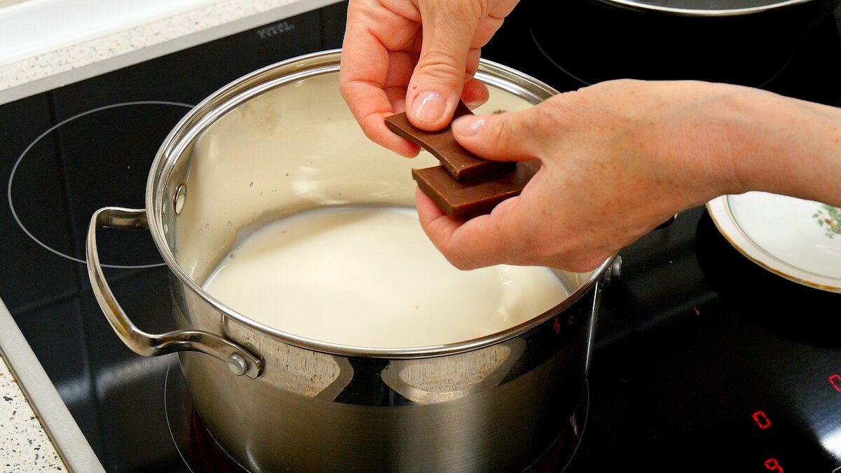 600-800 миллилитров молока ставим на сильный огонь. Молоко можно взять кокосовое: оптимально 6% жирности. Если жирнее, то лучше разбавить водой. Одну стограммовую плитку молочного шоколада ломаем на квадратики и закидываем в нагревающееся молоко.
