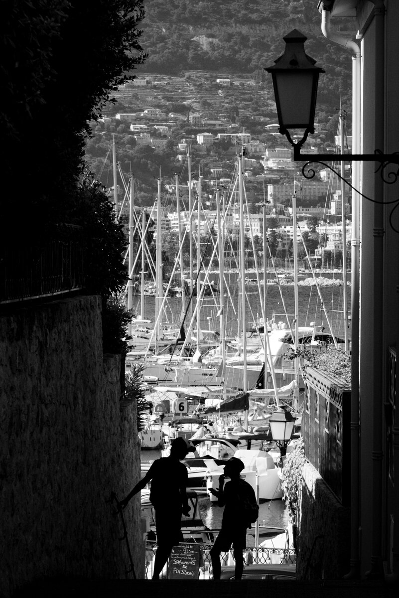 Силуэты людей, стоящих на лестнице на фоне порта.