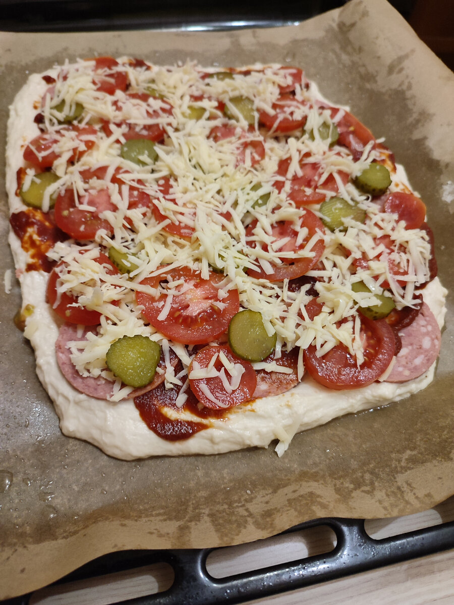 На тесто выложила варено-копченую колбаску, помазала томатной пастой, посыпала сыром, сверху помидоры, маринованный огурчик и сверху опять сыр 