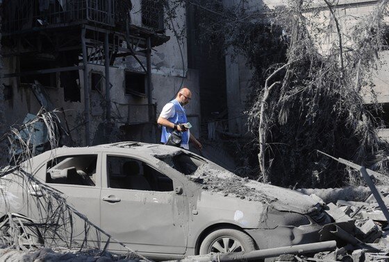    Сотрудник ООН среди обломков зданий, разрушенных во время израильской бомбардировки