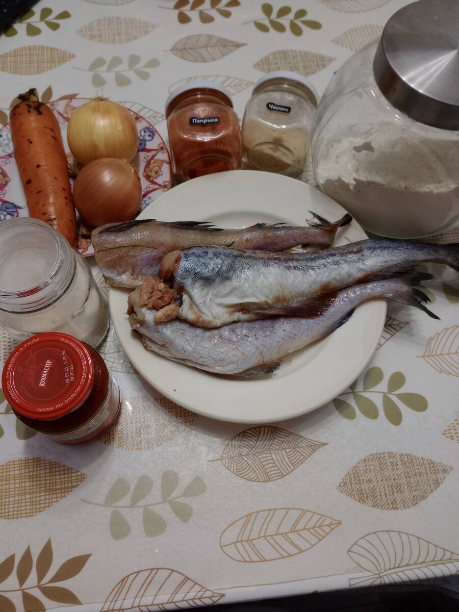 Продукты: 1.	Минтай – у меня было где-то 500 грамм.
2.	Мука – 2-3 столовые ложки.
3.	Лук – 2 шт.
4.	Морковь – 1 шт.
5.	Томатная паста – 2 столовые ложки.
6.	Сахар – 1 чайная ложка.
7.	Соль, перец и любимые приправы – по вкусу.
8.	Масло подсолнечное – для жарки.

