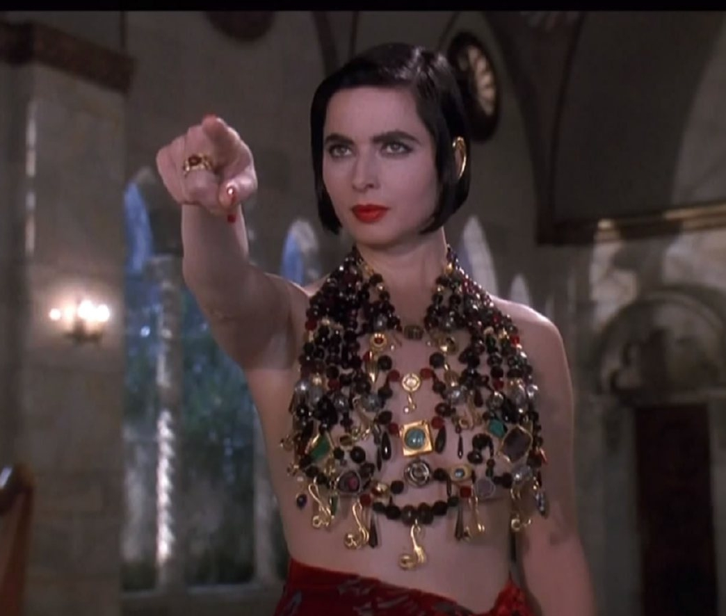 Ожерелье из «драгоценных» камней вместо блузки. Еще и перстень с красным камнем впридачу. Красный цвет символизирует страсть, kpовь. Самоцветы дают понять, что перед нами богатая женщина, которая любит себя и гордится своим телом. 