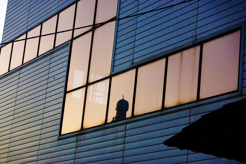 Отражение минарета с полумесяцем в окнах соседнего дворца художественной гимнастики