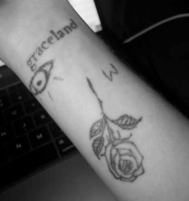 Внутри ее правой предплечья есть татуировка в виде розы