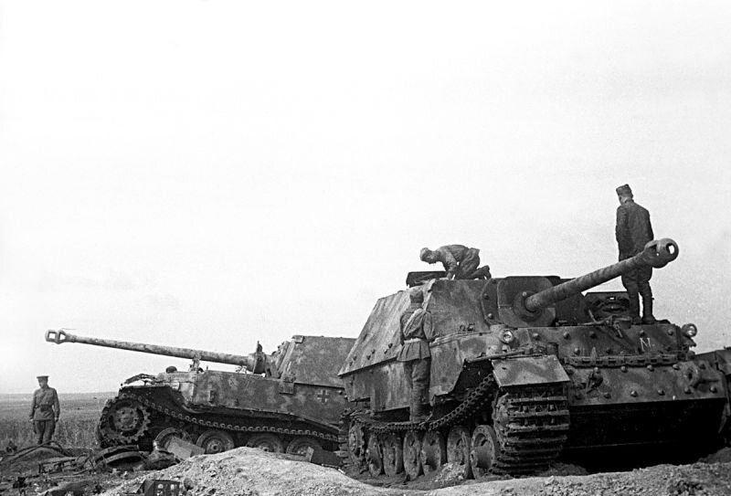Истребители танков «Фердинанд» Sd.Kfz.184 (8,8 cm PaK 43/2 Sfl L/71 Panzerjäger Tiger (P) штабной роты 654-го батальона тяжёлых истребителей танков (Schwere Panzerjäger-Abteilung 654) вермахта, подбитые 15-16 июля 1943 года в районе станции Поныри. Слева штабная машина № II-03. Была сожжена бутылками с керосиновой смесью после попадания снаряда, повредившего ходовую часть. В кадре советские военные. Источник фото: https://waralbum.ru/365407/