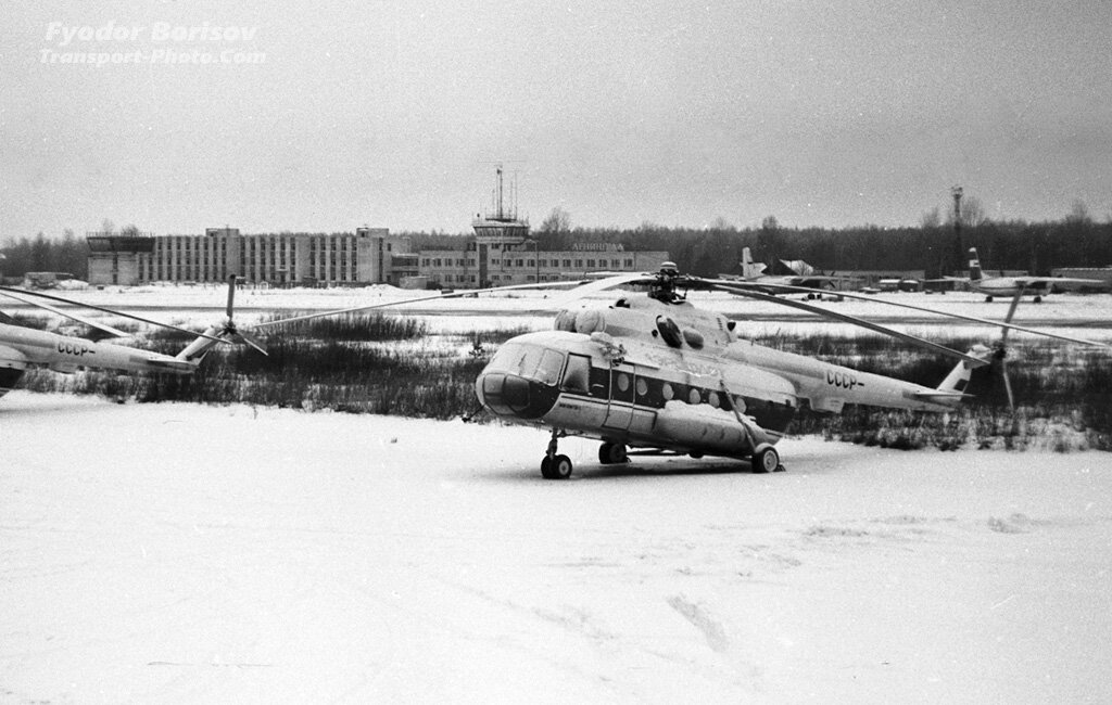 1. В декабре 1993 года Ржевка выглядела так. Рядом со старым терминалом, с вывеской "Ленинград", громоздился незаконченный, новый. Тогда на него возлагались надежды, но достроен он так и не был. На перроне у аэровокзала стоят Ан-26 (один из двух в авиаотряде) и рядом Ан-30. На переднем плане свеженькие тогда совсем новые Ми-8МТВ-1, некоторые ещё без регистрации. 