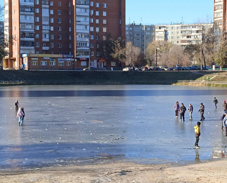    Дети гуляют по льду пруда, хотя в его середине вода еще не замерзла