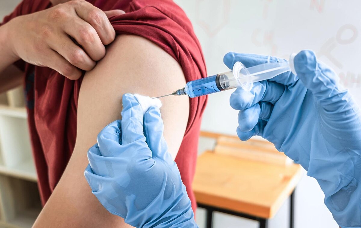    Doctor making a vaccination into patient with needle getting immune vaccine at arm for flu shot, coronavirus protective of epidemic.