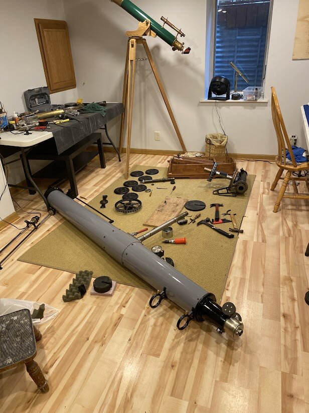 Труба рефрактора и детали, разложенные в мастерской.