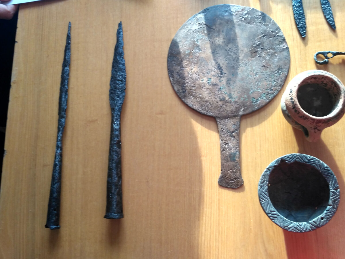 Предметы из погребения: железные наконечники копий, бронзовое зеркало, керамика.