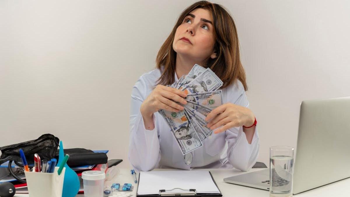    Девушка за рабочим столом с купюрами в руках:Freepik