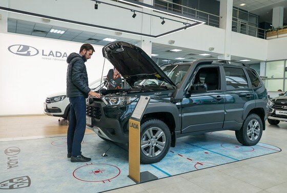    Мужчина осматривает автомобиль Niva Travel в автосалоне дилерского центра Lada